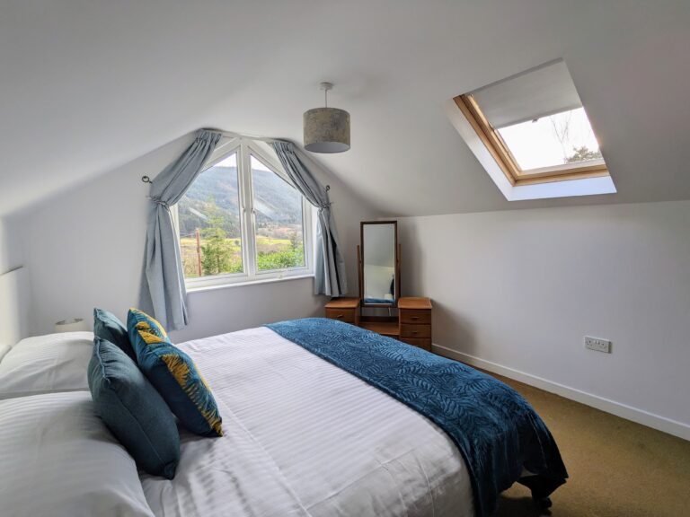 View across superking bed, and out window, Roosley cottage