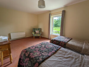 Twin bedroom with carpeted floor, large window, and armchair, Carnaclasha, no. 9, Rostrevor Holidays