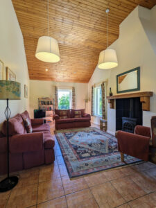 Living room with two sofas and an armchair, with a jotul wood stove and high wooden ceilings, Carnaclasha, no. 9, Rostrevor Holidays