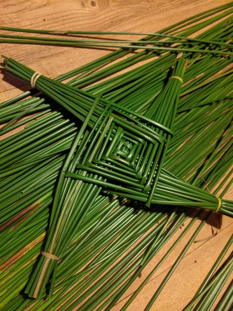 A green cross on a pile of rushes. This is a St. Brigid's Day cross